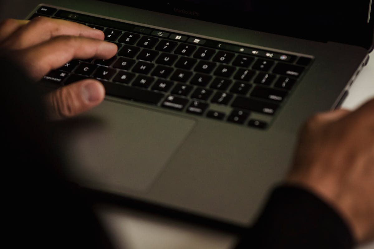 Hacker typing on laptop with cybersecurity data on screen representing AI agents in offensive and defensive security