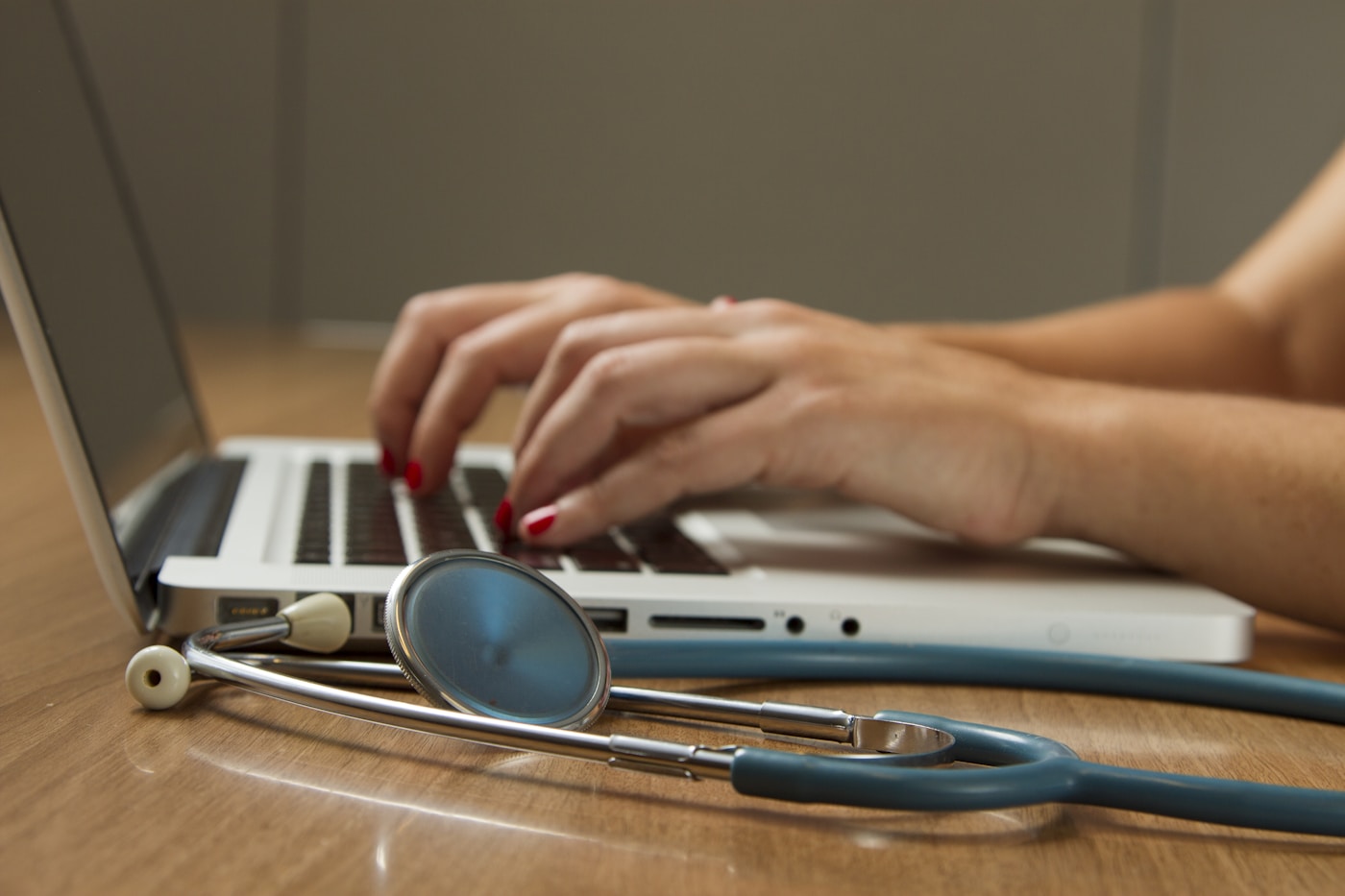Medical professional typing on laptop with stethoscope representing AI agents in healthcare clinical decision support